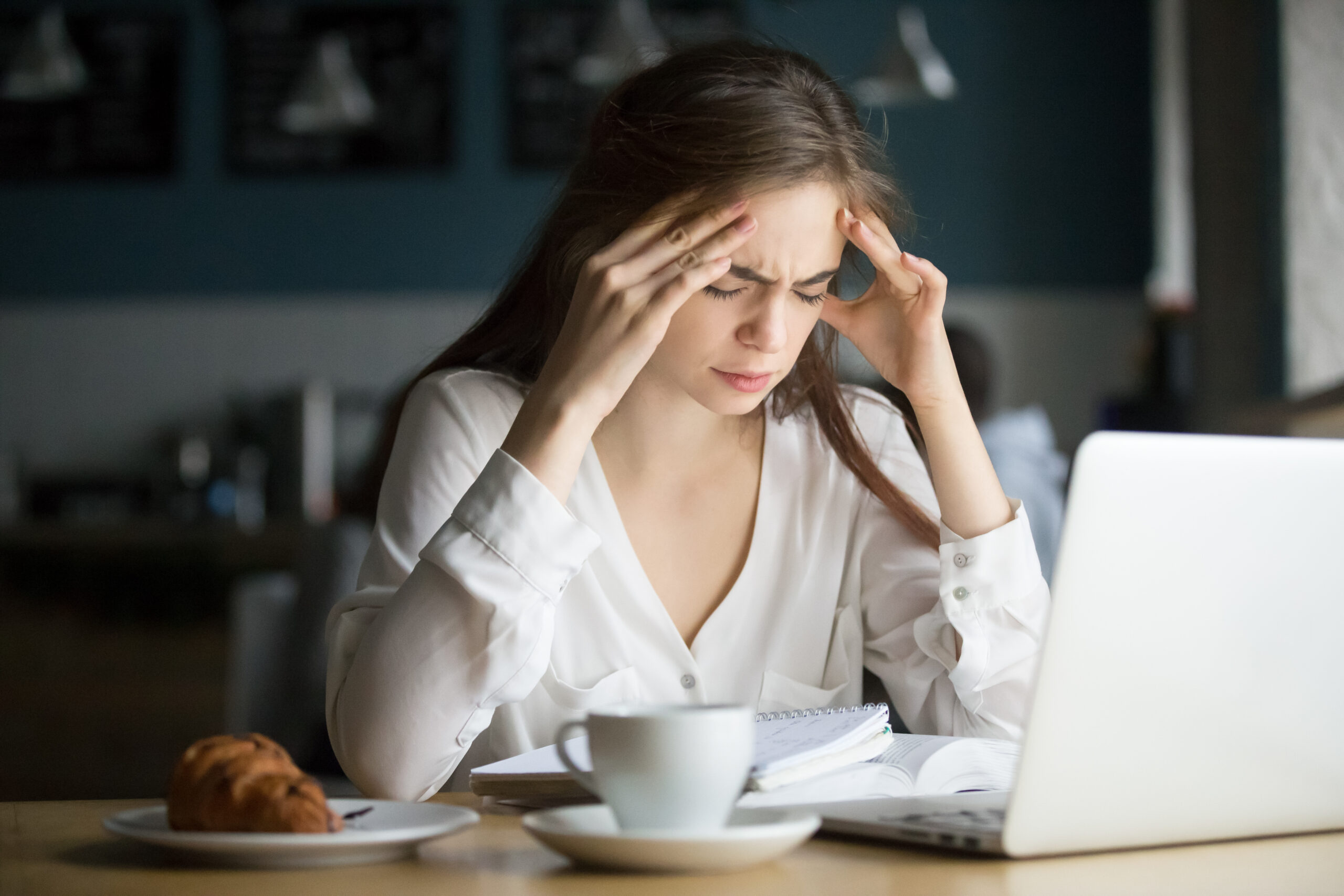 nervous stressed female student feeling headache studying in caf