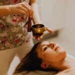 Young woman experiencing relaxation therapy with a singing bowl indoors.