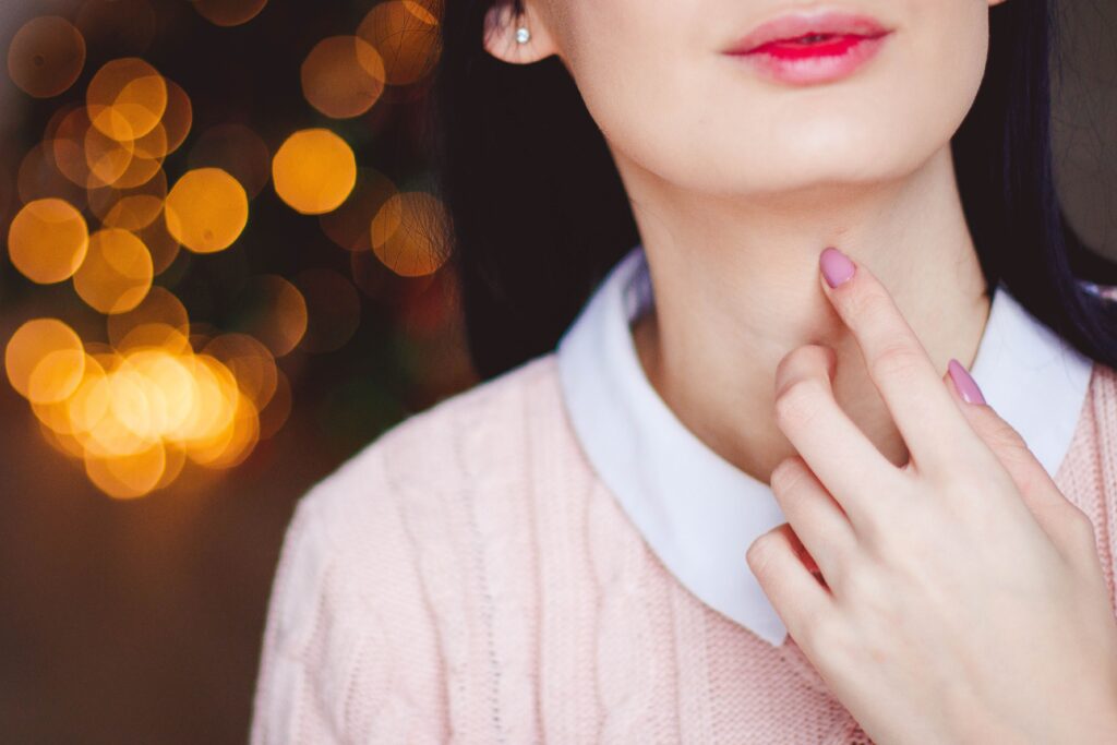 La voix : ce pouvoir invisible qui harmonise le corps et l’esprit Close-up of a woman's face and hand with a bokeh background, showcasing style and elegance.